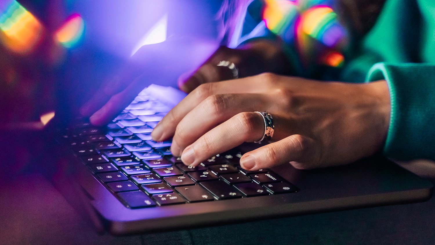 Hands typing on a keyboard with prismatic lens flares