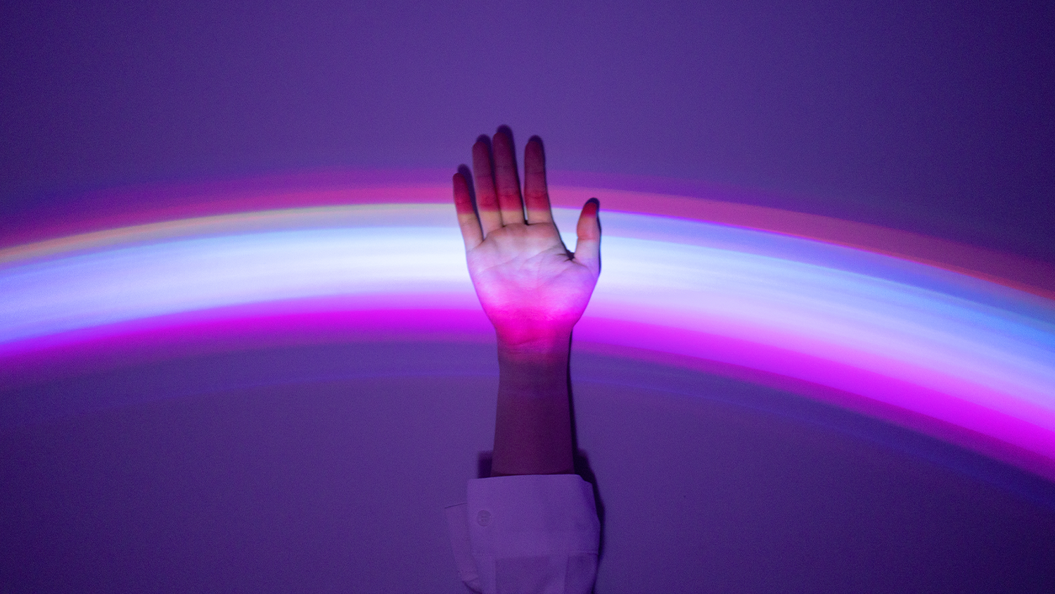 Hand against a dark background with an arc shining across the hand