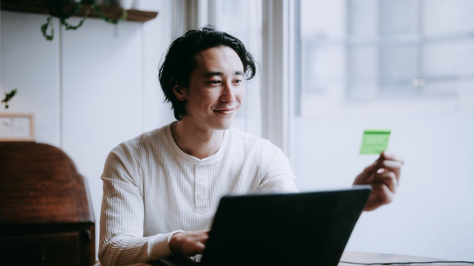 Man looking at credit card while using a laptop